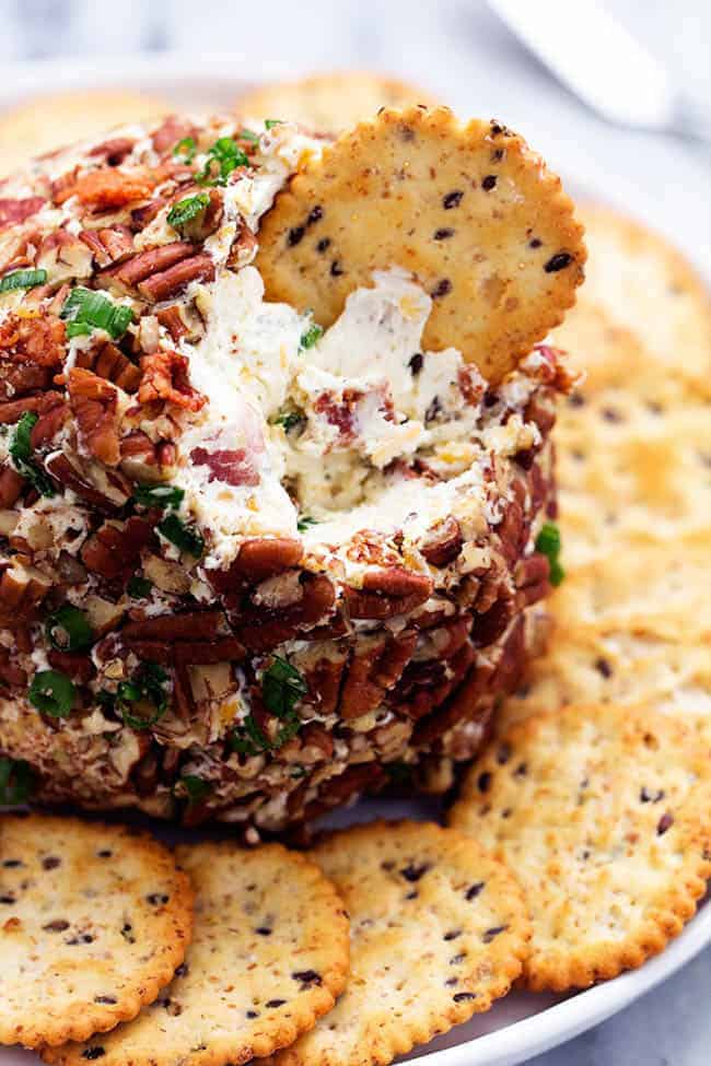 This bacon ranch cheese ball will be your favorite go-to appetizer! The winning combination of bacon, ranch seasoning, and cheddar cheese really stands out in this tasty cheese ball. Serve with crackers and watch everyone devour it! Close view of bacon ranch cheese ball with a crackers dipping.