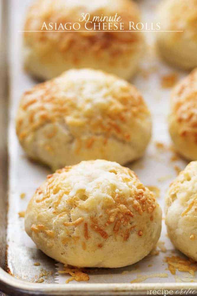 These rolls are made with quick and easy dough and are ready in 30 minutes! With delicious Asiago Cheese on top of these soft and perfect rolls, they are sure to be a hit! asiago cheese rolls on a baking tray.