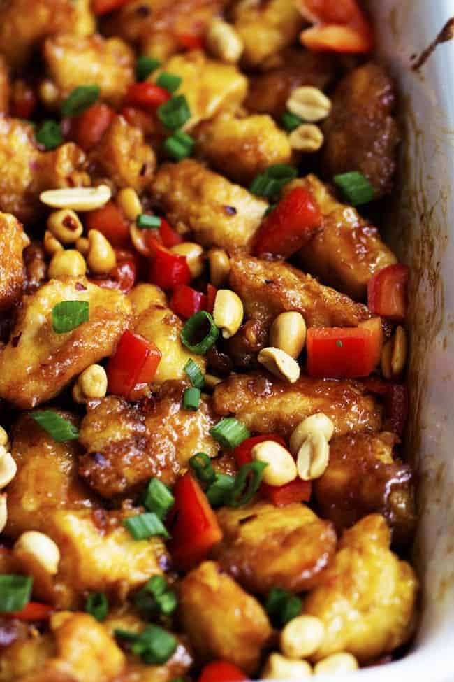 Delicious breaded chicken coated in a sweet and spicy sauce with peppers and peanuts hidden throughout. This is WAY better than any takeout you will have! Baked Kung Pao Chicken in a baking pan garnished with peanuts.