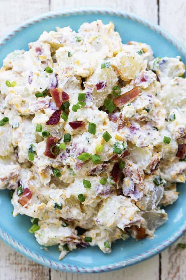 A creamy and delicious potato salad with amazing ranch flavor and bacon! This is the perfect side to take to a potluck and is sure to be a huge hit! bacon ranch potato salad on a blue plate.