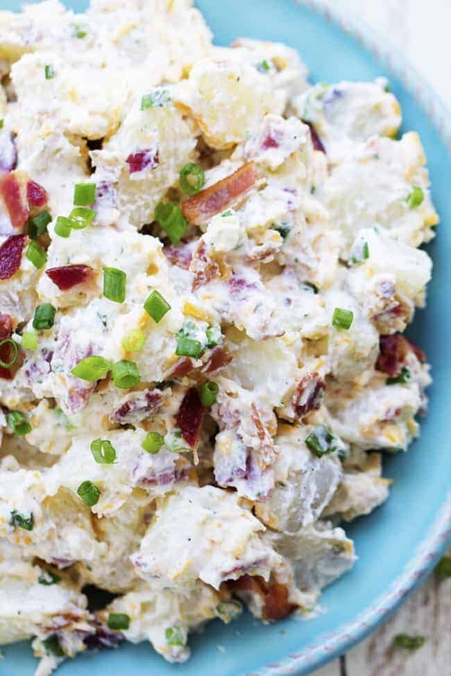 A creamy and delicious potato salad with amazing ranch flavor and bacon! This is the perfect side to take to a potluck and is sure to be a huge hit! bacon ranch potato salad on a blue plate.