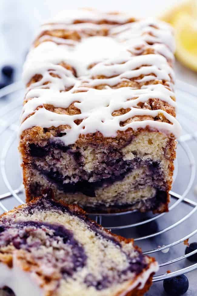 An amazingly moist muffin bread filled with blueberry pie filling. Topped with a crumb topping and drizzled in a lemon glaze this bread is incredible! Blueberry pie bread with the lemon glaze on a cooling rack.
