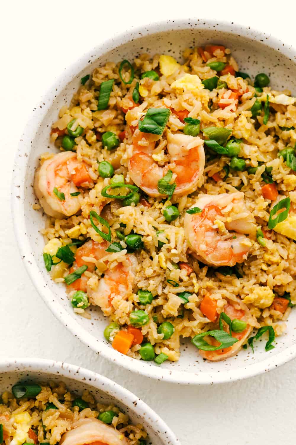 Skip the takeout! This shrimp fried rice is faster, fresher, and way more flavorful! Juicy shrimp, tender veggies, fluffy rice, and scrambled eggs all come together in one irresistible skillet meal. Shrimp fried rice in a bowl.
