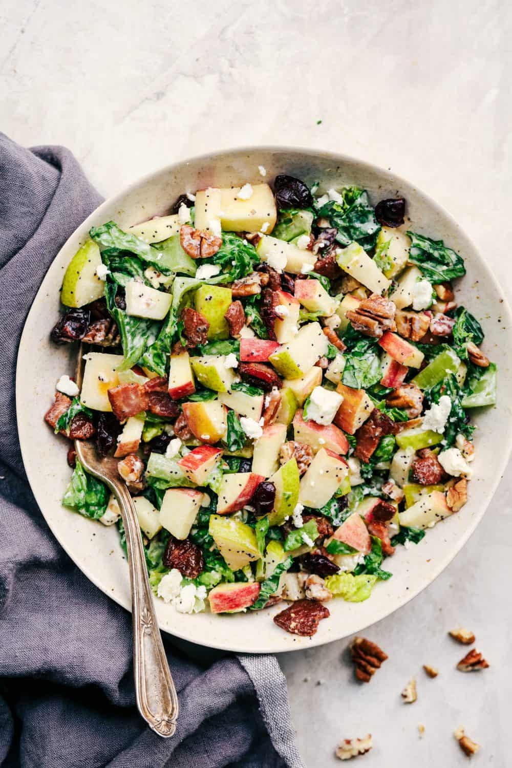 Autumn Chopped Salad with Creamy Poppyseed Dressing is all of your fall salad dreams come true! Crisp chopped apples, pears, romaine lettuce, crunchy pecans, bacon, cranberries and feta cheese combine in a creamy dressing to bring you one unforgettable salad! Autumn Chopped Salad with Creamy Poppyseed Dressing in a white bowl.