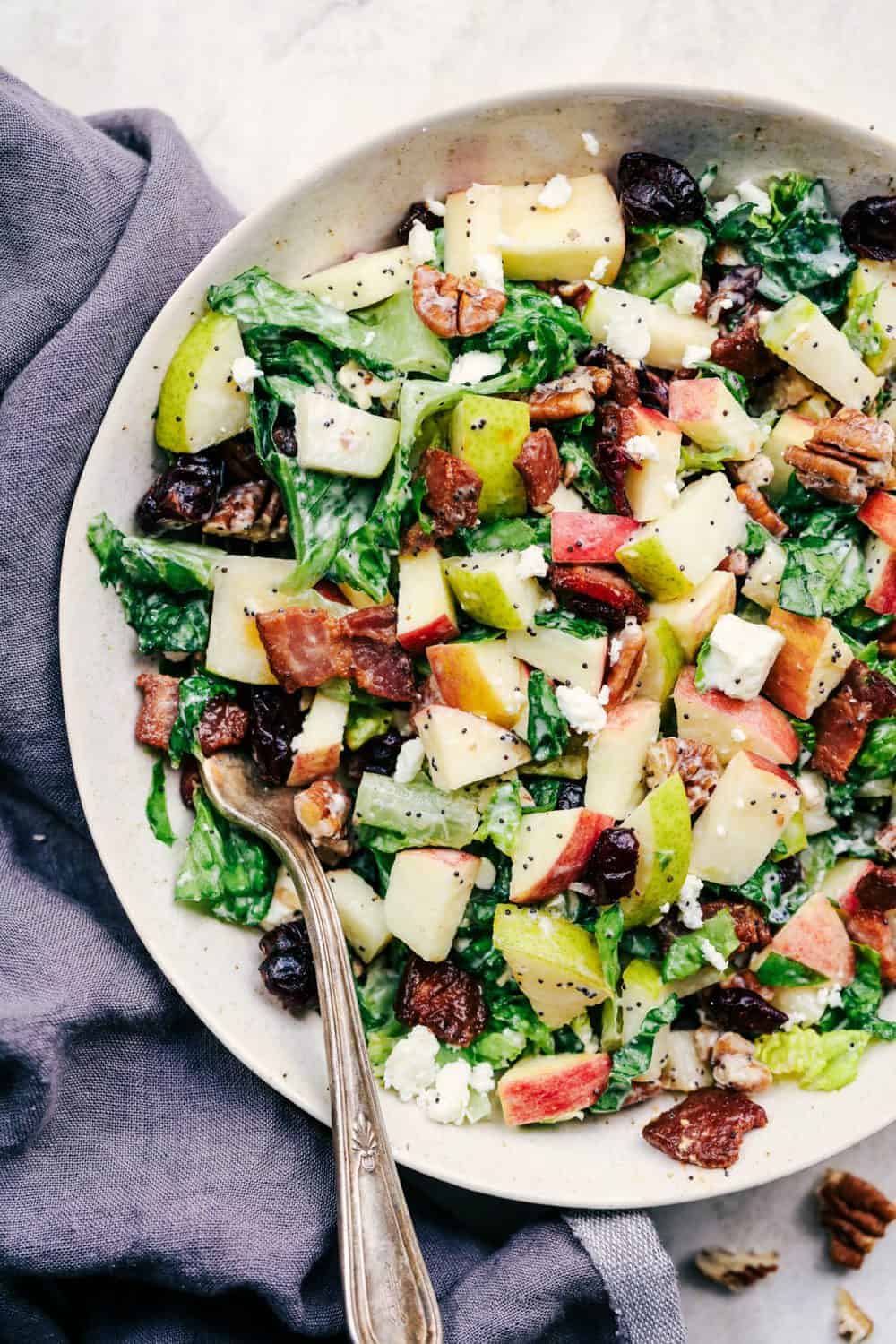 Autumn Chopped Salad with Creamy Poppyseed Dressing is all of your fall salad dreams come true! Crisp chopped apples, pears, romaine lettuce, crunchy pecans, bacon, cranberries and feta cheese combine in a creamy dressing to bring you one unforgettable salad! Autumn Chopped Salad with Creamy Poppyseed Dressing in a white bowl.