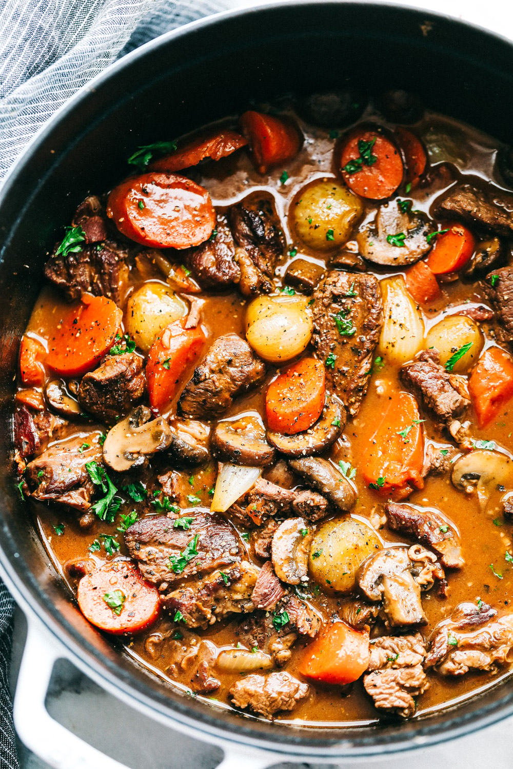 Beef Bourguignon is a French classic made with melt in your mouth beef, mushrooms, carrots, and red wine and is cooked to perfection in the most delicious rich sauce. A hearty and comforting meal that you will make again and again! Areal view of Beef Bourguignon.