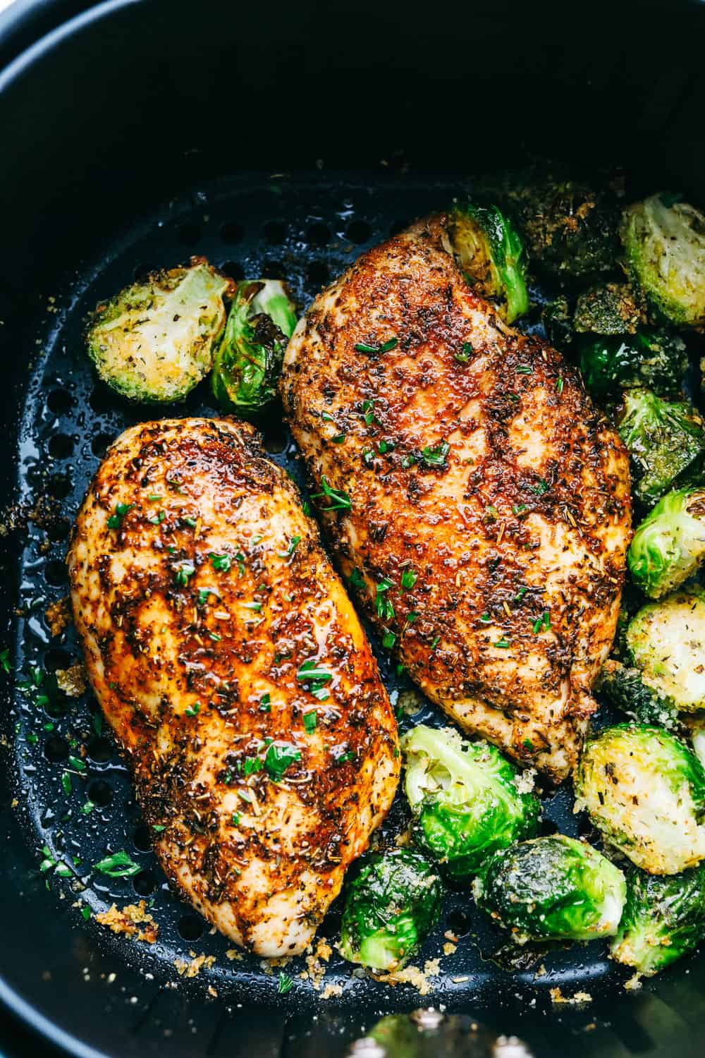 With this Air Fyer Chicken recipe, I am going to show you how to make the most insanely tender and juicy chicken! The secret? The incredible seasonings! They create a nice golden, crispy outside with a juicy, flavor-packed inside! Overhead shot of tender and juicy air fryer chicken cooked in the air fryer basket.