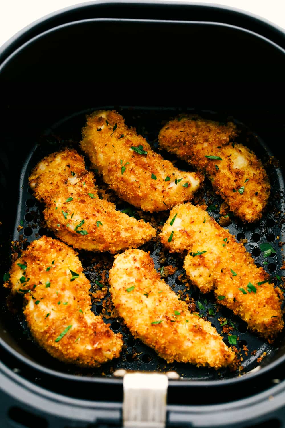 These air fryer chicken tenders are a lifesaver on crazy weeknights. Crispy, cheesy, and full of flavor—plus they cook up fast and my kids actually ask for seconds. Total win! Breaded and cooked chicken in the air fryer basket.