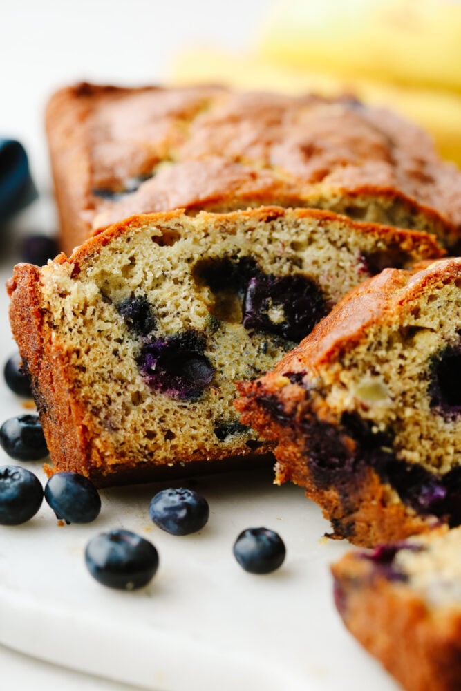 This staple blueberry banana bread recipe has the perfect combination of bananas and fresh blueberries. It is so moist, delicious, and super simple to make! Closeup of blueberry banana bread slices.