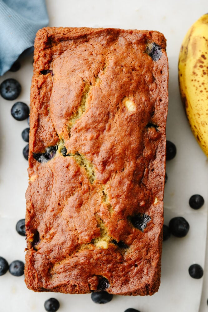 This staple blueberry banana bread recipe has the perfect combination of bananas and fresh blueberries. It is so moist, delicious, and super simple to make! A loaf of blueberry banana bread.