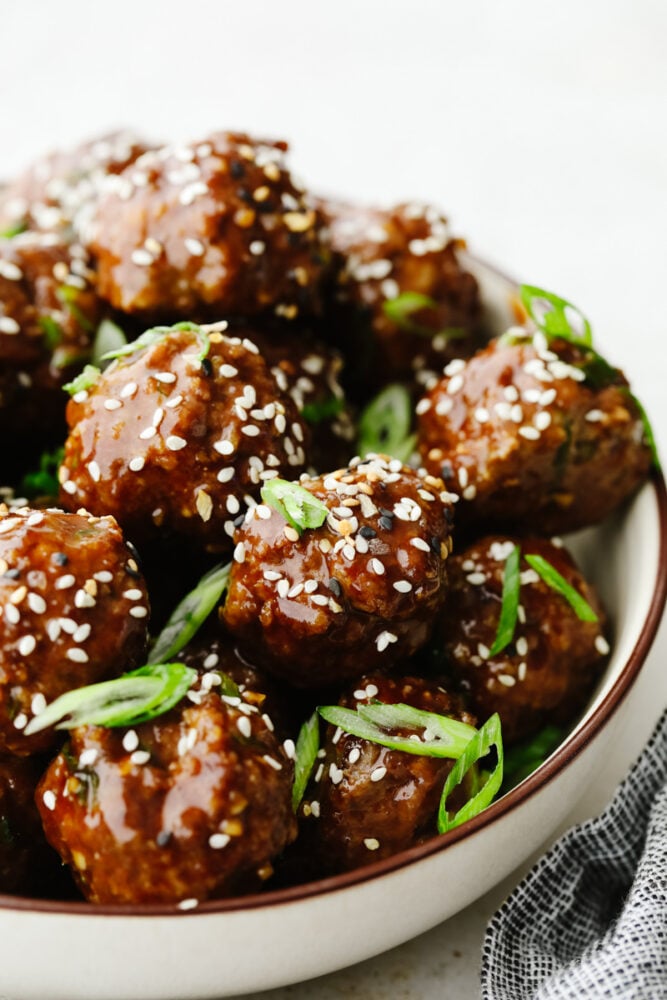 These saucy Asian meatballs are the perfect blend of flavors and are drenched in the most insanely delicious sauce! Perfect for dinner or even an appetizer, they will certainly get a "WOW!" at your next get-together! Asian meatballs in a bowl.