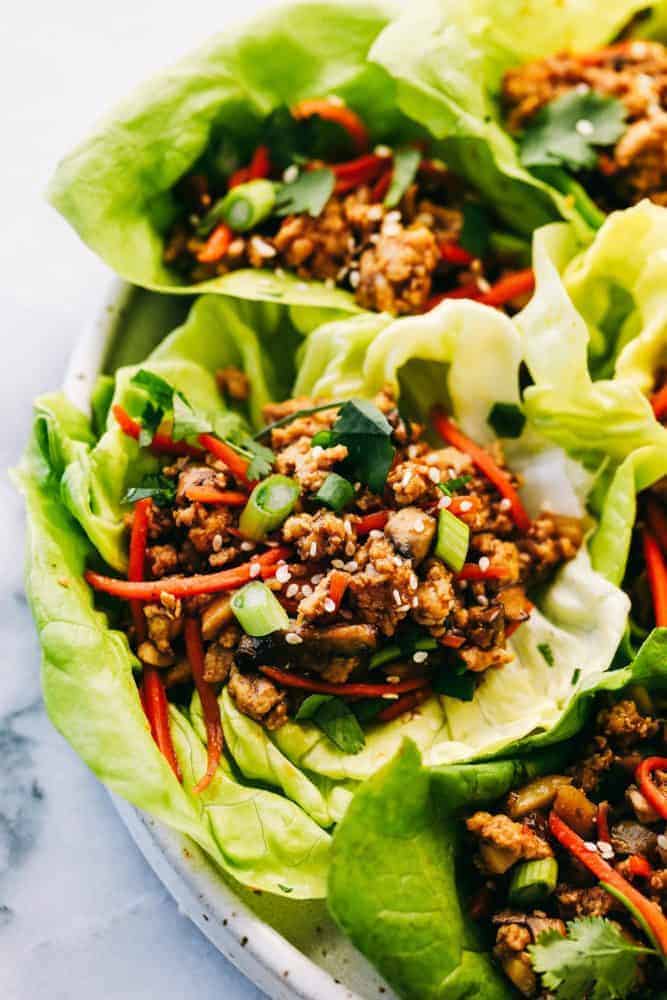 Asian turkey lettuce wraps are packed with intense flavor from tender meat and seasoned, crunchy veggies. These light and tasty wraps are the perfect healthy appetizer or even dinner! A zoomed in picture of a lettuce wrap garnished with sesame seeds.